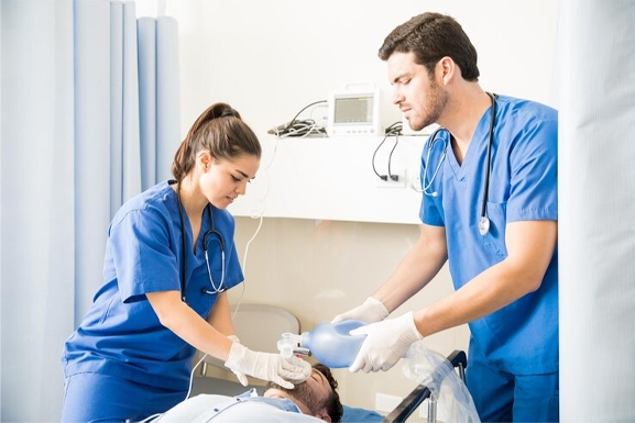 Nurses in a clinical setting using a manual ventilator on a patient in hospital bed